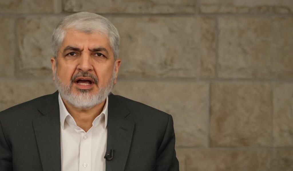 Άνδρας με γκρίζα γενειάδα μιλά μπροστά σε τοίχο