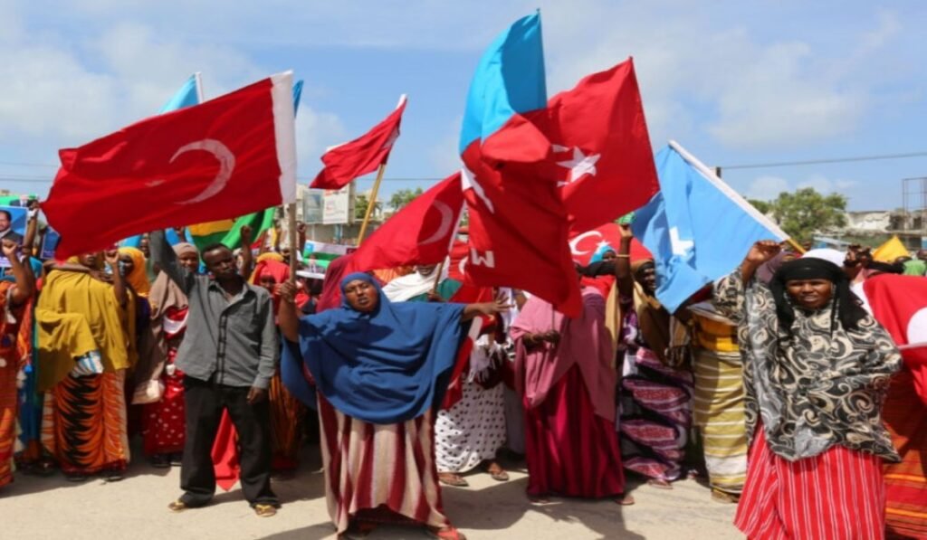 Πλήθος ανθρώπων με σημαίες σε υπαίθρια συγκέντρωση