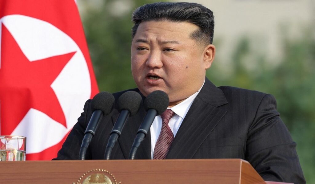 Άνδρας μιλά σε μικρόφωνα μπροστά σε σημαία