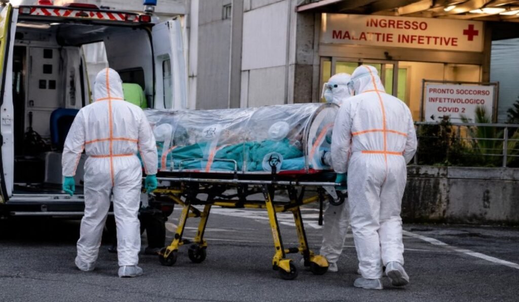 Υγειονομικοί με ειδικές στολές μεταφέρουν ασθενή σε νοσοκομείο της Ιταλίας υπό πρωτόκολλα βιοασφάλειας
